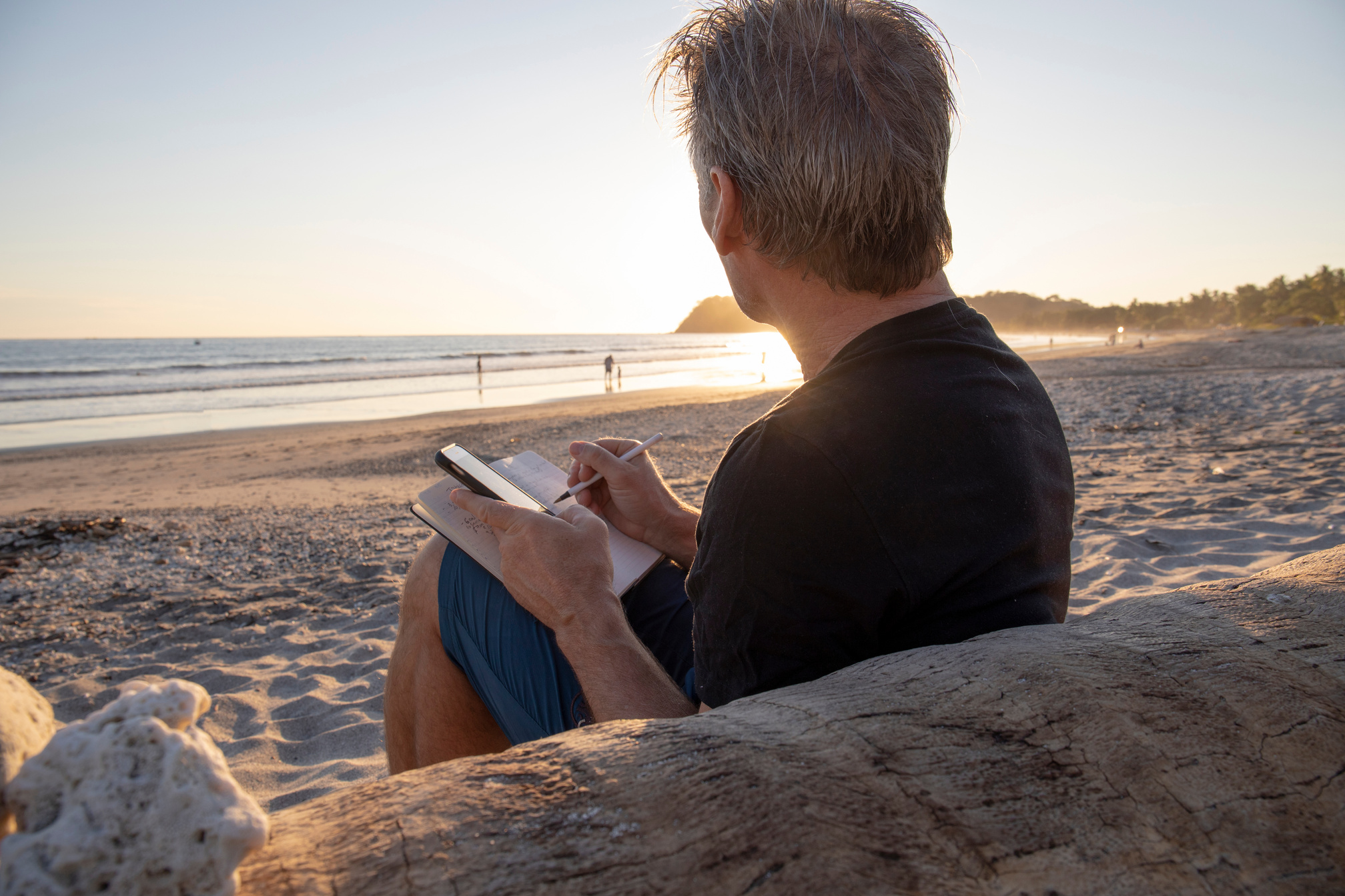 Man relaxes on beach, writes in journal