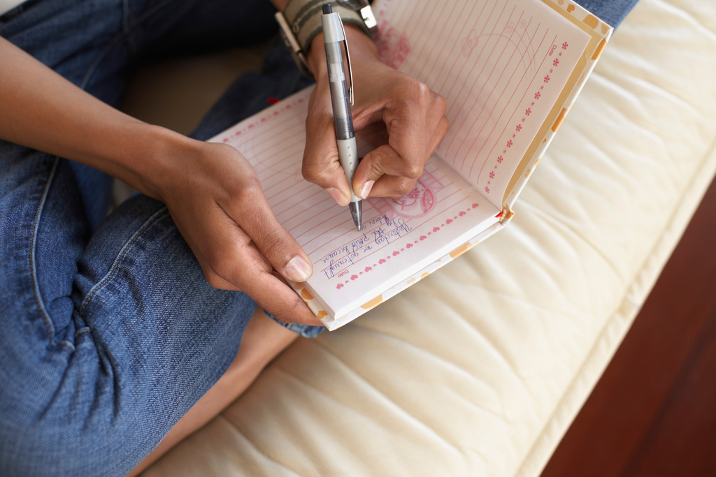 Woman's hands writing in journal